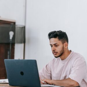 Un hombre trabaja en su computador portátil sobre una mesa, con su sitio y su correo en orden